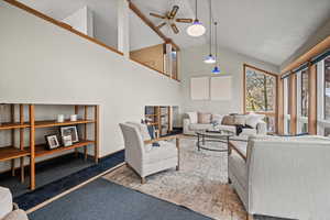 Living room featuring dark carpet, high vaulted ceiling, and ceiling fan