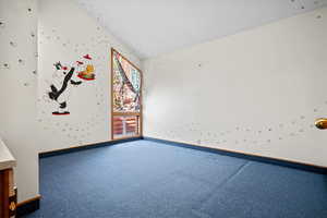 Empty room featuring carpet floors, vaulted ceiling, and pool table