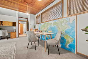 Carpeted dining room with built in desk, crown molding, and wood ceiling