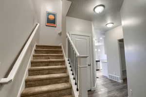 Staircase featuring sink, wood-type flooring, and a textured ceiling