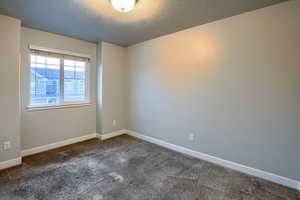 Carpeted empty room featuring a textured ceiling