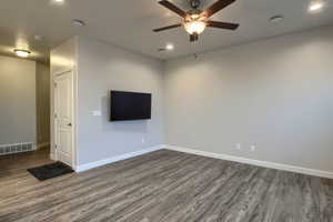 Unfurnished living room with ceiling fan and dark wood-type flooring