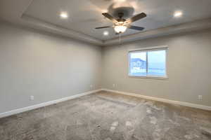 Unfurnished room with a tray ceiling, ceiling fan, and carpet floors