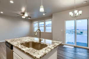 Kitchen featuring white cabinetry, sink, dark wood-type flooring, pendant lighting, and a center island with sink