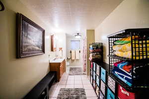 Corridor with light tile patterned floors, a textured ceiling, and sink