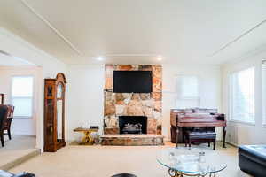 Carpeted living room with a fireplace and crown molding