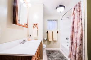 Full bathroom featuring toilet, vanity, shower / tub combo with curtain, and tile patterned flooring