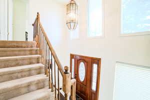 Entrance foyer with carpet flooring and a chandelier