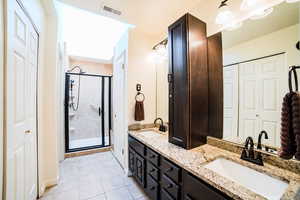 Bathroom with tile patterned floors, vanity, and a shower with door