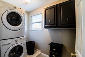 Laundry room featuring cabinets and stacked washer / drying machine