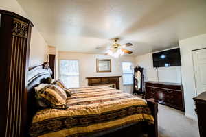 Carpeted bedroom with a textured ceiling and ceiling fan