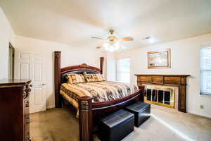 Carpeted bedroom with multiple windows and ceiling fan