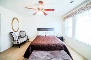 Bedroom with ceiling fan and light carpet