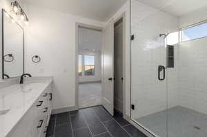 Bathroom with tile patterned floors, vanity, a healthy amount of sunlight, and an enclosed shower