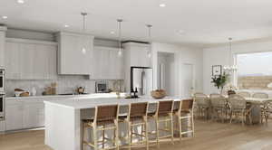 Kitchen featuring white cabinetry, stainless steel fridge, a kitchen island with sink, black electric stovetop, and light wood-type flooring*Rendering