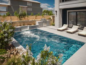 View of swimming pool featuring area for grilling, a patio area, pool water feature, and exterior kitchen*Rendering