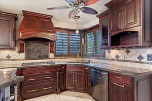 Kitchen with custom exhaust hood, dark stone counters, sink, light tile patterned floors, and stainless steel appliances