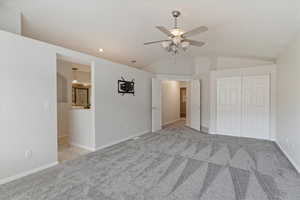 Unfurnished bedroom featuring ceiling fan, light colored carpet, lofted ceiling, and a closet