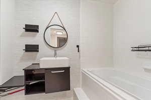 Bathroom featuring vanity and tiled bath