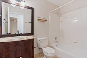 Full bathroom with vanity, tiled shower / bath combo, and toilet