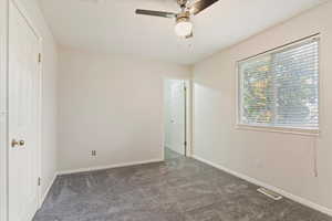 Unfurnished bedroom featuring ceiling fan and dark colored carpet