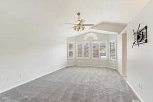 Carpeted empty room featuring vaulted ceiling and ceiling fan