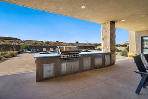 View of patio with an outdoor kitchen, a mountain view, and grilling area