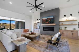 Living room with ceiling fan, a fireplace, and light hardwood / wood-style flooring