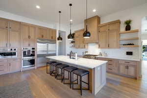 Kitchen featuring a kitchen breakfast bar, a center island with sink, light hardwood / wood-style flooring, and appliances with stainless steel finishes