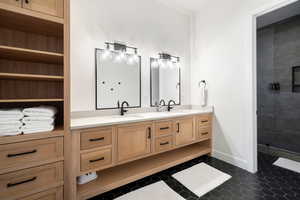 Bathroom featuring tile patterned flooring, vanity, and walk in shower