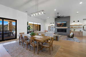 Dining space featuring a large fireplace, ceiling fan, and light hardwood / wood-style flooring