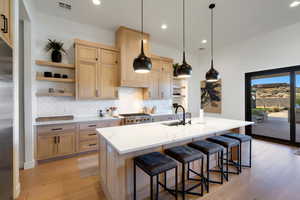 Kitchen with a kitchen bar, sink, an island with sink, and light hardwood / wood-style floors