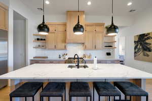 Kitchen featuring light brown cabinets, light hardwood / wood-style floors, and an island with sink