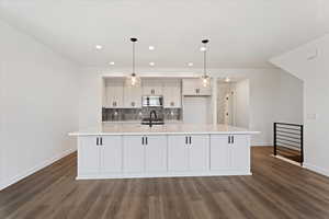 Kitchen featuring a large island with sink, backsplash, stainless steel appliances, and pendant lighting