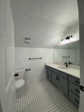 Bathroom with a textured ceiling, vanity, toilet, and lofted ceiling