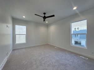 Spare room with ceiling fan, carpet floors, and a wealth of natural light