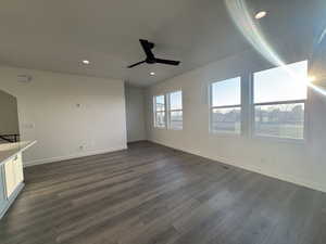 Unfurnished living room featuring ceiling fan and dark wood-type flooring