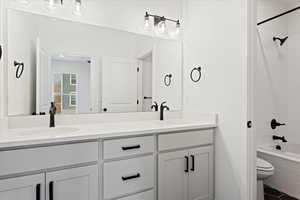 Full bathroom featuring vanity, tiled shower / bath combo, and toilet