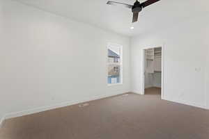 Unfurnished bedroom with carpet flooring, ceiling fan, a spacious closet, and a closet