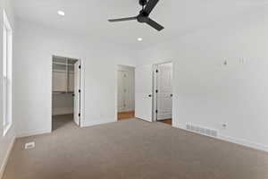 Unfurnished bedroom with light carpet, a closet, a spacious closet, and ceiling fan