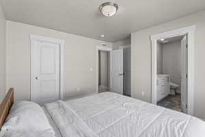 Bedroom featuring ensuite bath, a closet, and a textured ceiling
