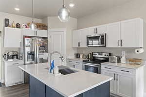 Kitchen featuring a center island with sink, sink, hanging light fixtures, dark hardwood / wood-style flooring, and stainless steel appliances