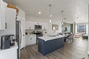 Kitchen featuring sink, an island with sink, pendant lighting, white cabinets, and appliances with stainless steel finishes