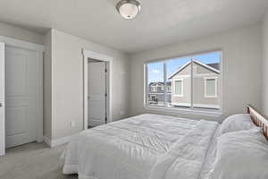 Bedroom with a textured ceiling and light colored carpet