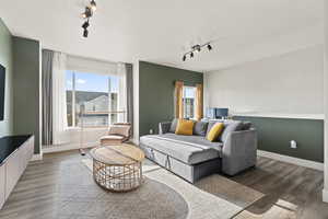 Living room with a textured ceiling, dark hardwood / wood-style flooring, and rail lighting