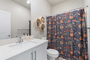 Bathroom featuring a shower with curtain, vanity, and toilet