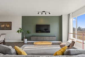 Living room with a textured ceiling, track lighting, and dark wood-type flooring