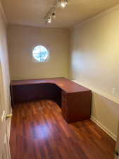 Unfurnished office with a textured ceiling, dark wood-type flooring, crown molding, and rail lighting