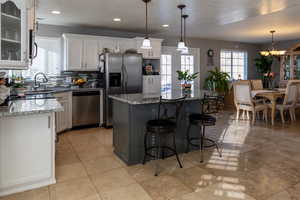 Kitchen with pendant lighting, a center island, white cabinetry, and stainless steel appliances