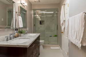 Bathroom featuring tile patterned flooring, toilet, an enclosed shower, and vanity